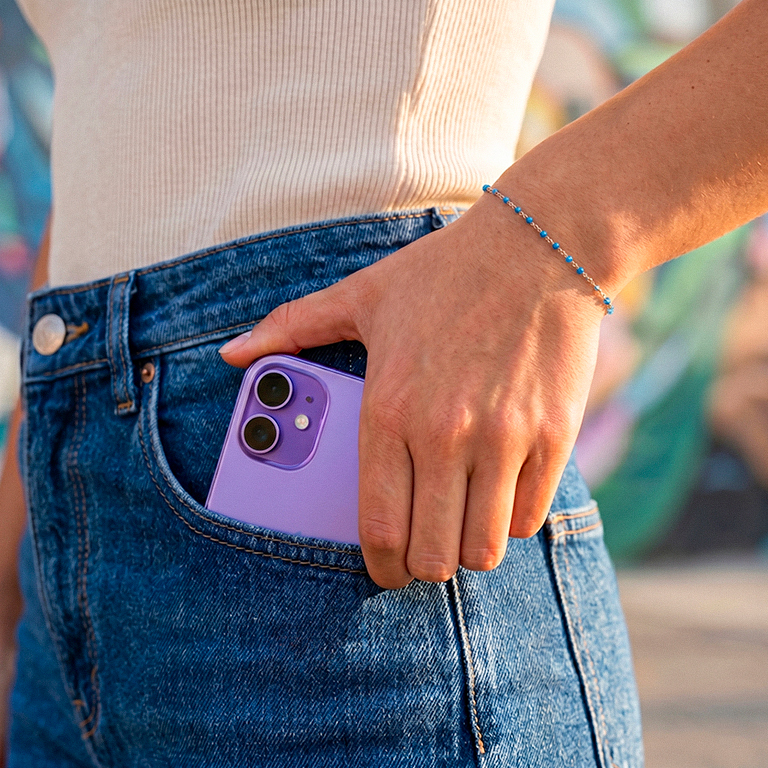 iPhone violet dans poche jean avec bracelet bleu lifestyle